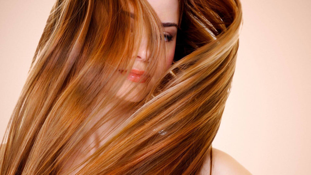 woman with red hair in face pink background