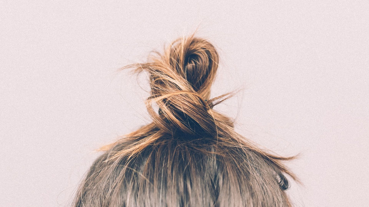 hair in a bun pink background